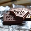 Pieces of The Good Chocolate with the logo embossed, resting on a foil wrapper.